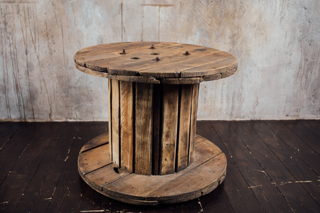 old wooden reel against concrete wall backgroundの写真素材