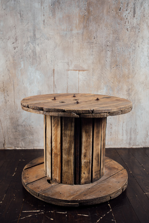 old wooden reel against concrete wall backgroundの写真素材