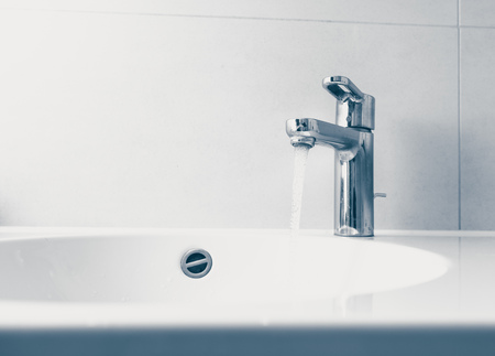 faucet with flowing water in wash sinkの写真素材