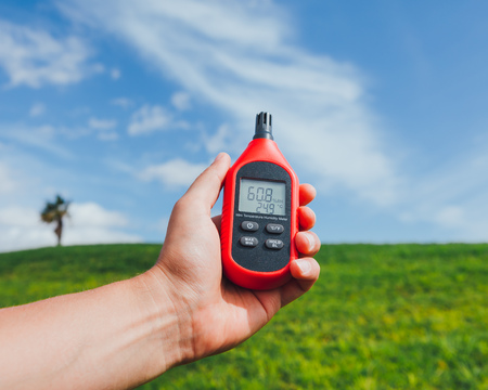 portable thermometer in hand measuring outdoor air temperature and humidity