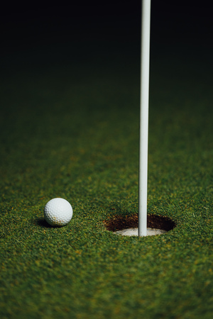 golf ball nearby hole with pin flag, green grass background, closeup viewの写真素材