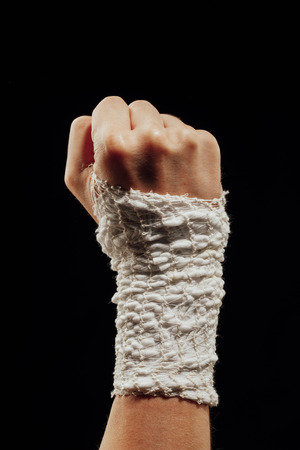 wrist wrapped with healing bandage, isolated on blackの写真素材