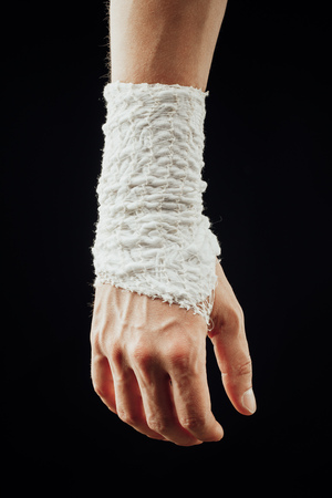 wrist wrapped with healing bandage, isolated on blackの写真素材