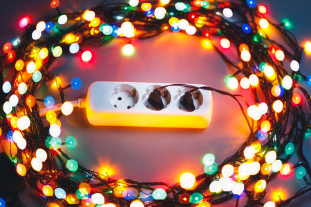 Christmas garland lights circle around electric extension cord