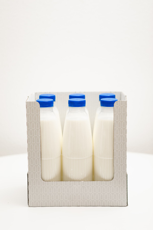 milk bottles in cardboard box on white tableの写真素材