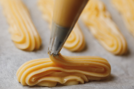 raw eclairs choux pastry on the baking trayの写真素材