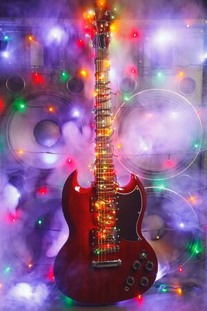 electric guitar with festive Christmas lights and music speakers in smokeの写真素材