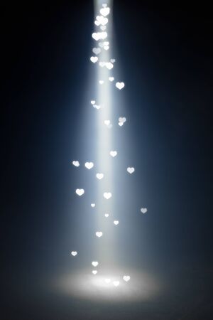 glowing heart shapes particles in spot lightの写真素材