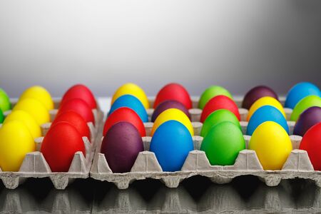 Easter festive multicolor eggs carton, gray background with copy-space