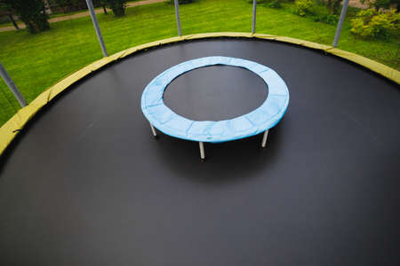small trampoline on big one with round mat, size comparison, green lawn backgroundの写真素材