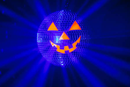 Halloween party pumpkin disco ball, jack-o-lantern with shiny rays in smokeの写真素材