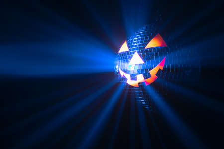 Halloween party pumpkin disco ball, jack-o-lantern with shiny rays in smokeの写真素材
