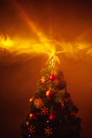 Christmas tree with festive lights, orange background with smokeの写真素材