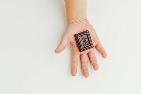 child holding a piece of dark chocolate bar in handの写真素材