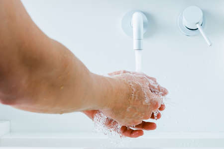 hands under the mixer spout with flowing water