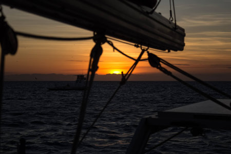 The sun sets into the coast. View from a sailing boat anchored at Lizard Iceland, Queensland, Australiaの写真素材