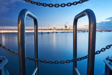 Elements of a Pier in foreground and Auckland's skyline in the background. A unique long exposure of a cruise ship departing from Auckland's harbor in the midground, painting the image with its light.の写真素材
