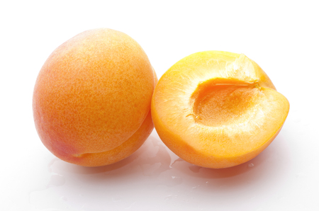 whole apricot and half close-up on white backgroundの写真素材