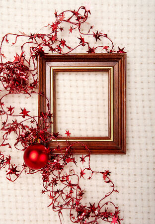 Classic wooden frame decorated with Christmas foil stars and red ball on wool plaid backgroundの写真素材