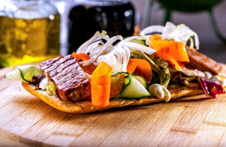 Bruschetta with meat and vegetable salad close-up on wooden boardの写真素材