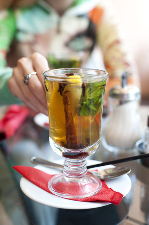 woman taking a glass of tea with lemon, cinnamon stick, mint, anise star and clovesの写真素材