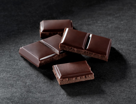 pieces of broken chocolate bar close-up on gray background