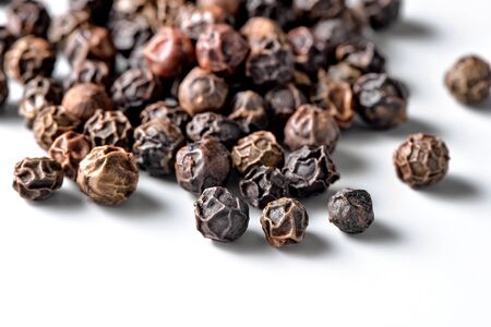 black allspice peppercorns close-up scattered on white backgroundの写真素材