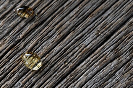 Transparent honey drops close-up on textured wooden boardsの写真素材