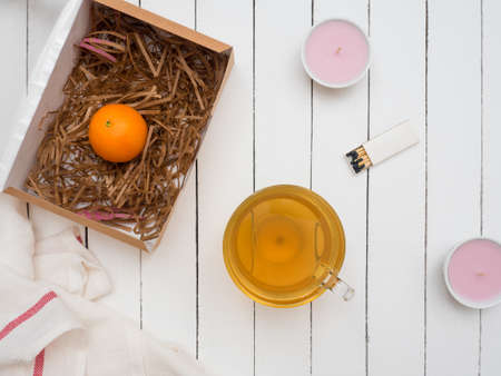 Large glass cup of green tea and a ripe tangerine on an old wooden table painted whiteの写真素材