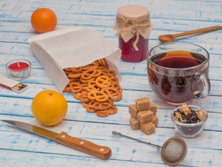 A large cup of black tea, lemon, jam jar and crackers on an old wooden table in French style