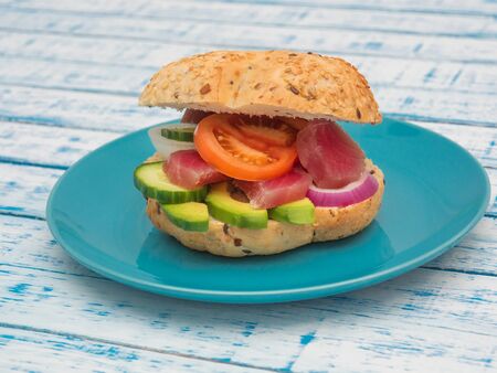 Sandwich with tuna and fresh vegetables in a plate on a wooden tableの写真素材