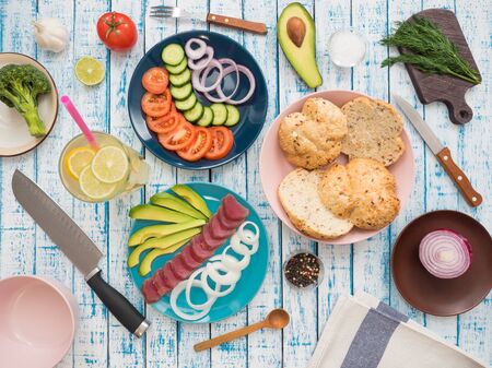 Sandwich with tuna and fresh vegetables in a plate and a glass of lemonade on a wooden tableの写真素材