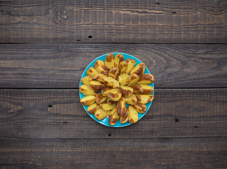Freshly baked potatoes in a plate on an old wooden tableの写真素材