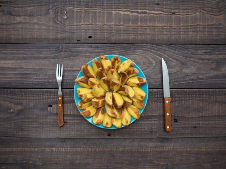 Freshly baked potatoes in a plate on an old wooden tableの写真素材