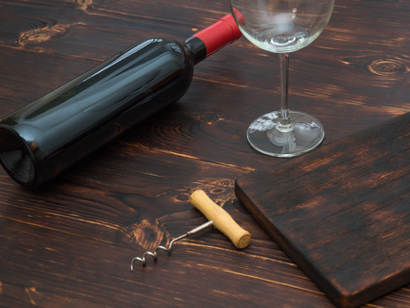 Bottle of red wine, a glass and a corkscrew on the tableの写真素材