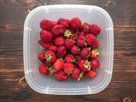 Berry strawberries with food container on a wooden tableの写真素材