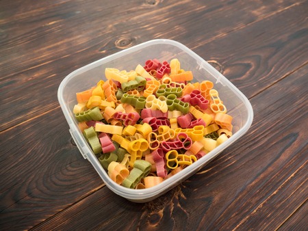 Italian multicolored pasta from hard wheat varieties of unusual shape in a food container on a table