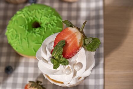 Candy bar. Cupcakes with blueberries strawberries and mint. Donuts in green and pink glaze with sprinkles.の写真素材