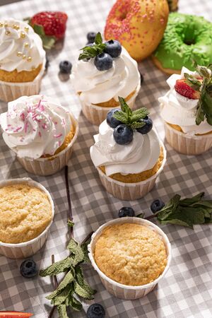 Candy bar. Cupcakes with blueberries strawberries and mint. Donuts in green and pink glaze with sprinkles.の写真素材