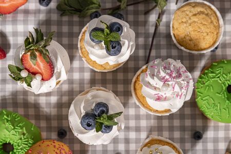 Candy bar. Cupcakes with blueberries strawberries and mint. Donuts in green and pink glaze with sprinkles.の写真素材