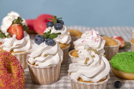 Candy bar. Cupcakes with blueberries strawberries and mint. Donuts in green and pink glaze with sprinkles.の写真素材
