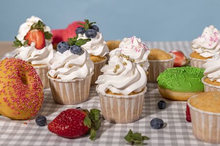 Candy bar. Cupcakes with blueberries strawberries and mint. Donuts in green and pink glaze with sprinkles.の写真素材