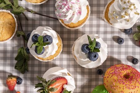 Candy bar. Cupcakes with blueberries strawberries and mint. Donuts in green and pink glaze with sprinkles.の写真素材