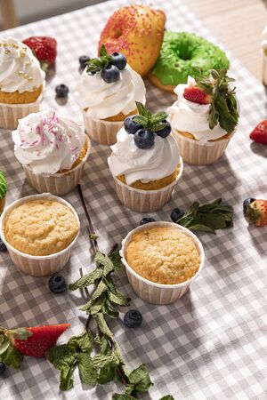 Candy bar. Cupcakes with blueberries strawberries and mint. Donuts in green and pink glaze with sprinkles.の写真素材