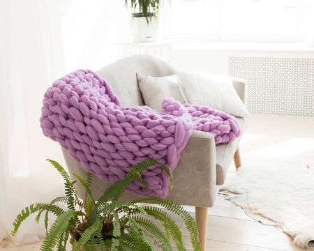 A large merino lilac plaid blanket lies on a sofa. Coarse violet plaid of merino wool. Plaid. Cozy interior. Handmadeの写真素材