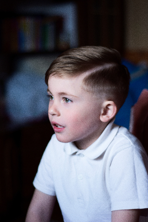 A cute boy is sitting in the room and admiring the wonderful landscapeの写真素材