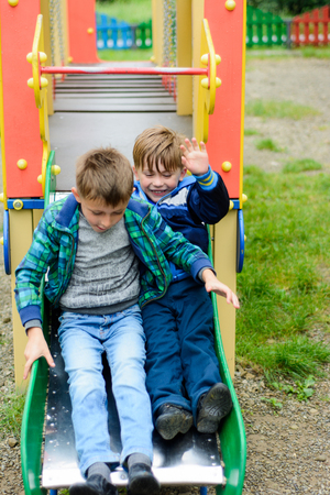 Beautiful Ukrainian boys run on a playground and descend from the hillsの写真素材