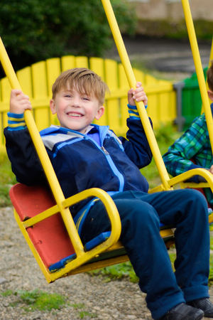Funny boys swing on a yellow swing-boardの写真素材