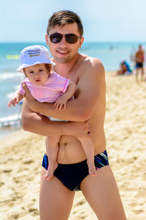 Young father in sunglasses on the beach with a little daughterの写真素材