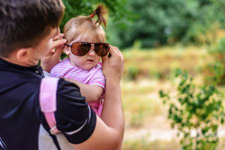 Amazing little girl is playing with sunglasses with her fatherの写真素材